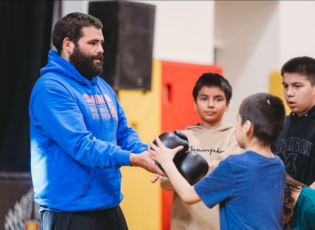 Cole Smith fitting boxing gloves on youth